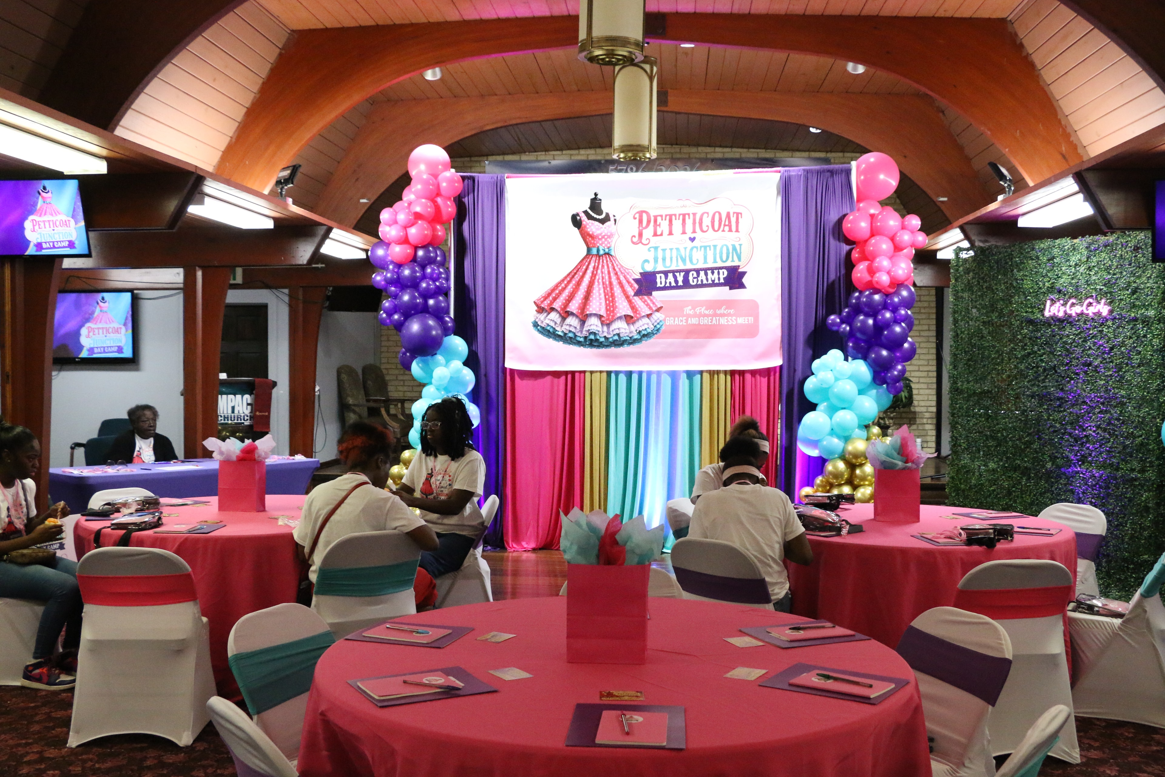 Petticoat Junction Day Camp venue with colorful balloon columns and branded stage backdrop